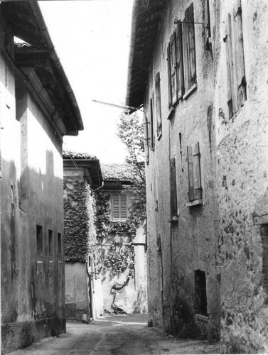 L'attuale via Battisti, con l'esterno della Curt di Ost sulla destra. In fondo a sinistra l'ingresso di Villa Castelbarco, direzione Galetera